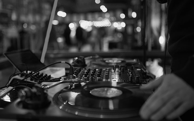 turntable, hand of dj on the vinyl record at night club. blured background
