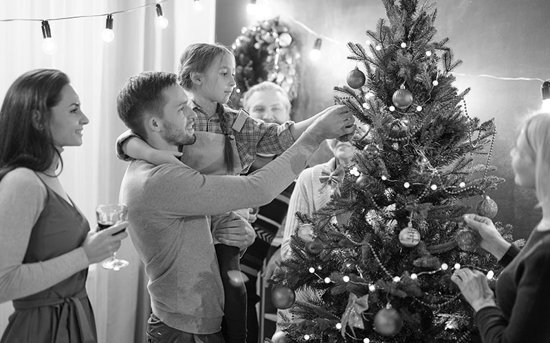 Young man with his little daughter decorating Christmas tree at home
