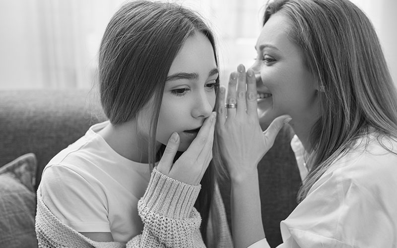 Mother gossiping with daughter at home

