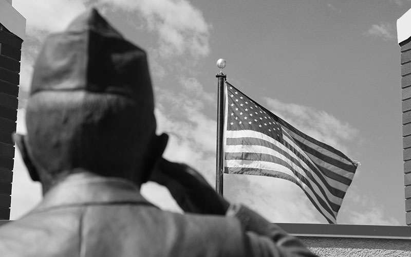 Salute to Veterans: Statue of soldier saluting with American flag flying in the background.
