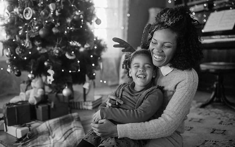 Joyful black mother and daughter laughing on Christmas day at home.